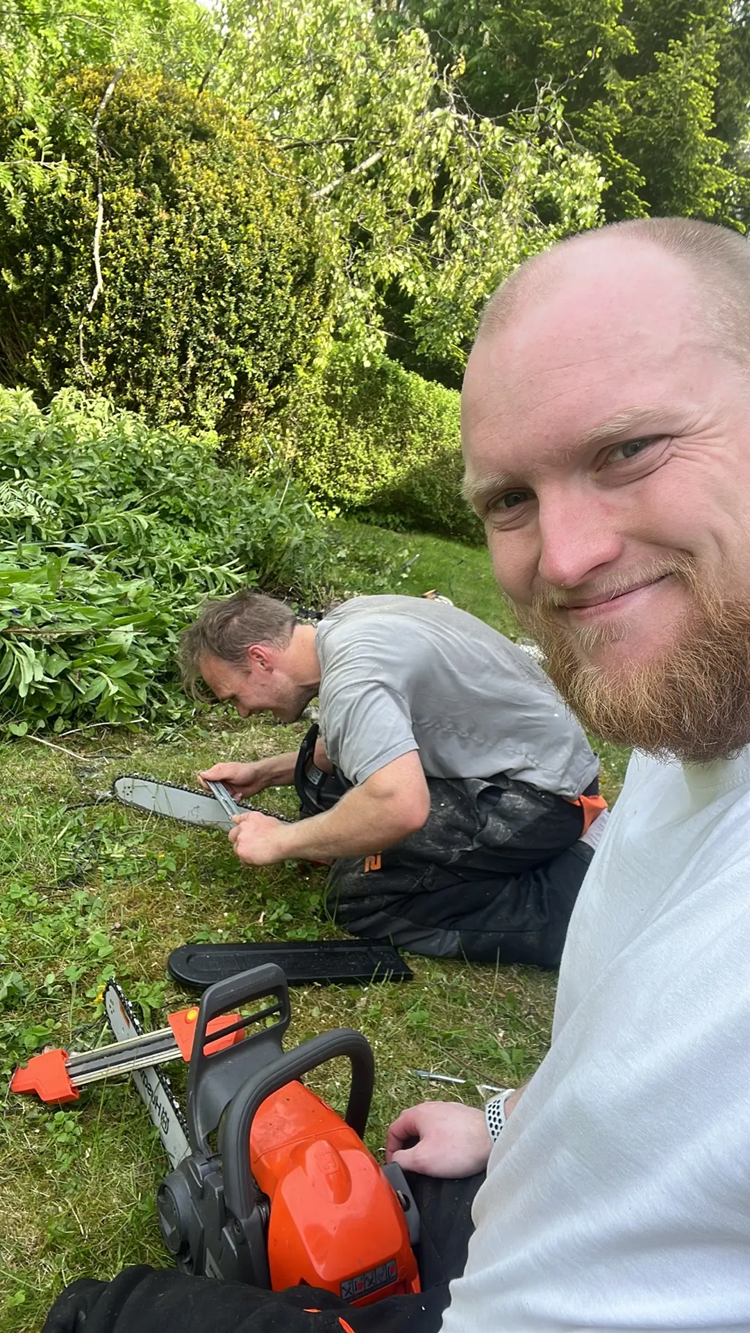 Selfie fra en jobb, med motorsag i gresset og kjedet som files i bakgrunnen